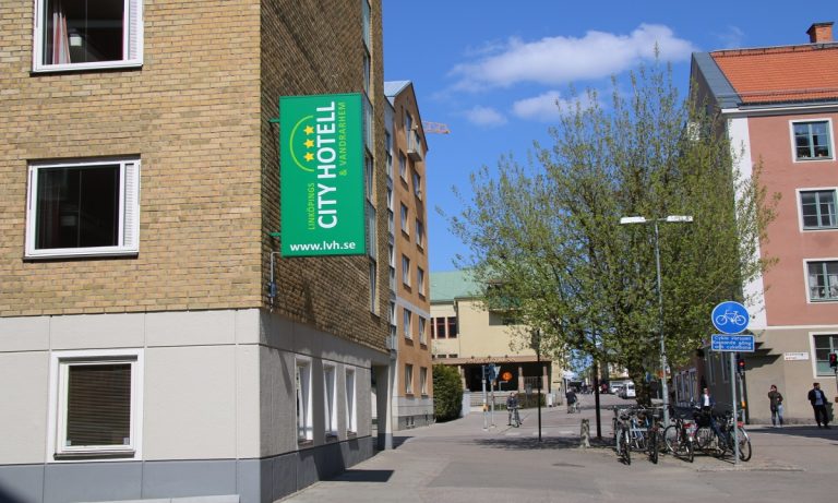 Linköpings City Hotell skylt som sitter på hotellfasad och gatuvy.